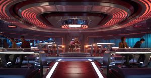 La plancia di comando di un'astronave di Star Trek, con il capitano al centro e l'equipaggio alle proprie postazioni. L'ambiente è futuristico, dominato da un'illuminazione rossa e da superfici metalliche.