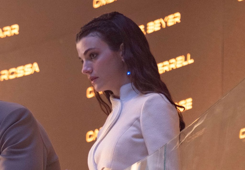 Tarima Sadal, con i capelli scuri e una luce blu sull'orecchio, in un'uniforme bianca futuristica.