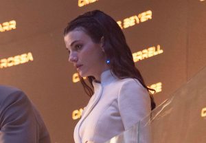 Tarima Sadal, con i capelli scuri e una luce blu sull'orecchio, in un'uniforme bianca futuristica.