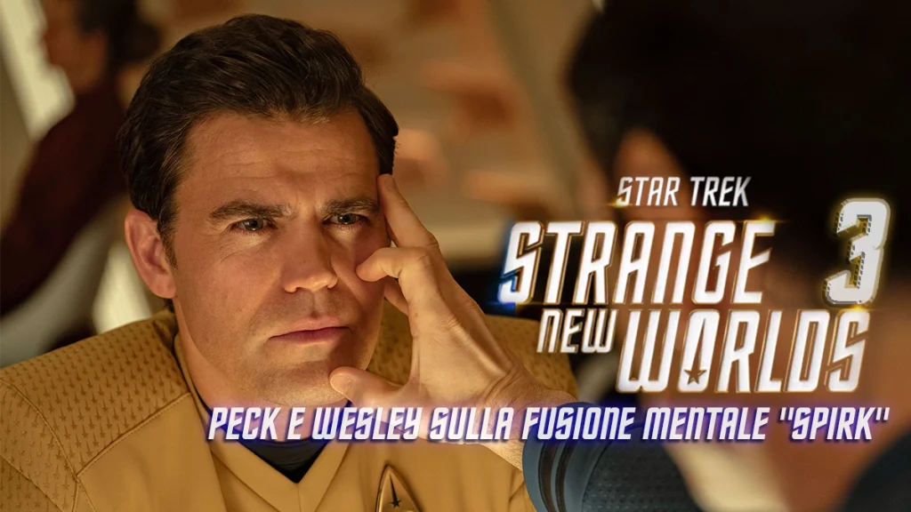Paul Wesley, nel ruolo del Capitano Kirk in "Star Trek: Strange New Worlds", è in primo piano con un'espressione concentrata. Ethan Peck di spalle tiene le dita sulla tempia di Paul, nella classica posa della fusione mentale vulcaniana. L'immagine ha una sovrapposizione di testo con il titolo della serie e la scritta "Peck e Wesley sulla fusione mentale 'Spirk'".