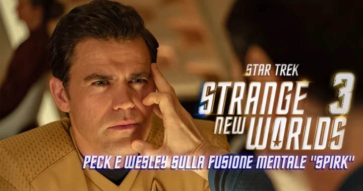 Paul Wesley, nel ruolo del Capitano Kirk in "Star Trek: Strange New Worlds", è in primo piano con un'espressione concentrata. Ethan Peck di spalle tiene le dita sulla tempia di Paul, nella classica posa della fusione mentale vulcaniana. L'immagine ha una sovrapposizione di testo con il titolo della serie e la scritta "Peck e Wesley sulla fusione mentale 'Spirk'".