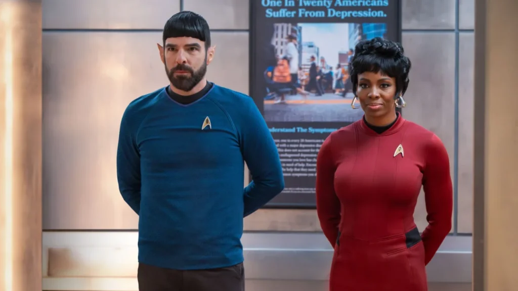 Zachary Quinto vestito da Spock, con uniforme blu e orecchie a punta, fa il saluto vulcaniano accanto a Tamberla Perry, vestita da Uhura con l'uniforme rossa, in un corridoio d'ospedale.